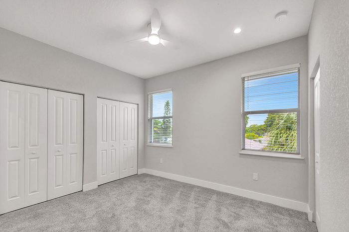 Bright and spacious bedroom featuring plush carpeting, ample closet space, and large windows offering scenic views.
