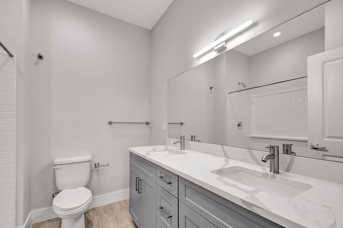 Modern bathroom with sleek marble countertop, stylish double sink, elegant gray cabinetry, and luxurious lighting.