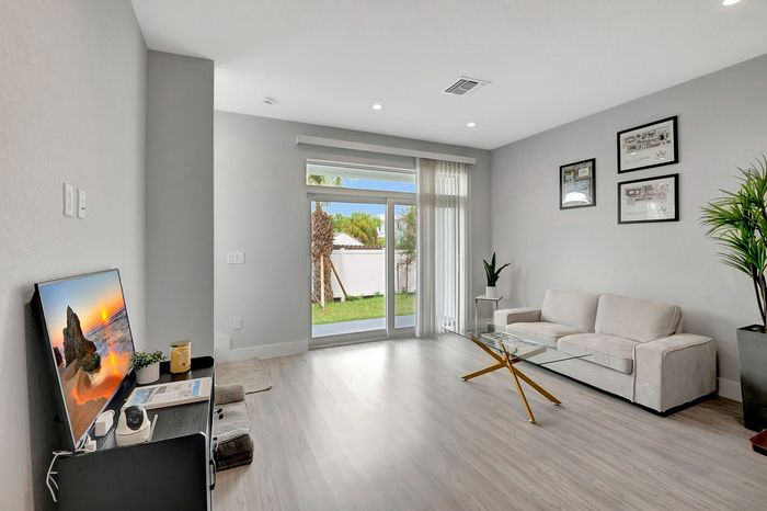 Bright modern living room with sleek decor, featuring a cozy sofa, elegant glass coffee table, and a view of the lush garden through large windows.