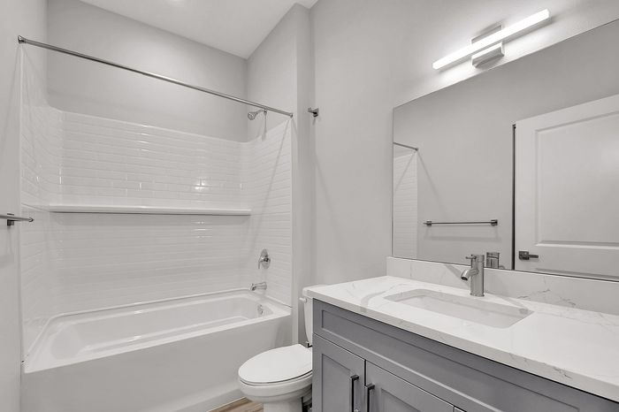 Bright and modern bathroom featuring a sleek vanity, elegant white tile, and a spacious bathtub.