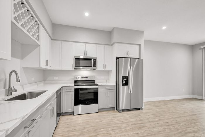 Modern kitchen with sleek stainless steel appliances, elegant white cabinetry, and pristine countertops, perfect for culinary enthusiasts.