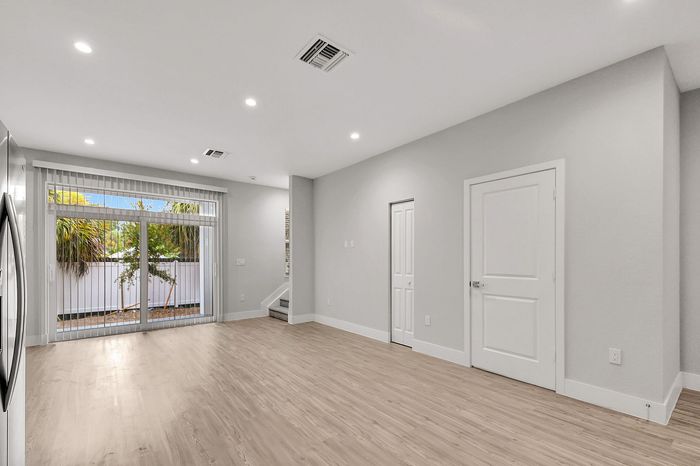 Contemporary open living space with elegant wood flooring, large glass doors, and abundant natural light.