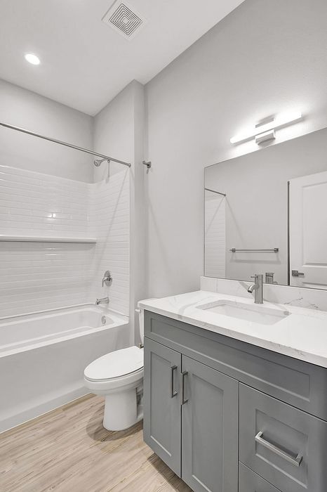 Modern bathroom design with elegant gray cabinetry, sleek marble countertop, and pristine white bathtub.