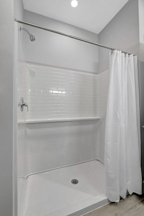 Sleek modern shower featuring elegant white subway tiles and a pristine white shower curtain.
