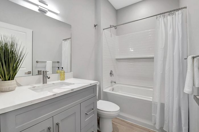 Elegant bathroom interior showcasing a modern vanity with a sleek faucet and a pristine bathtub with shower curtains.