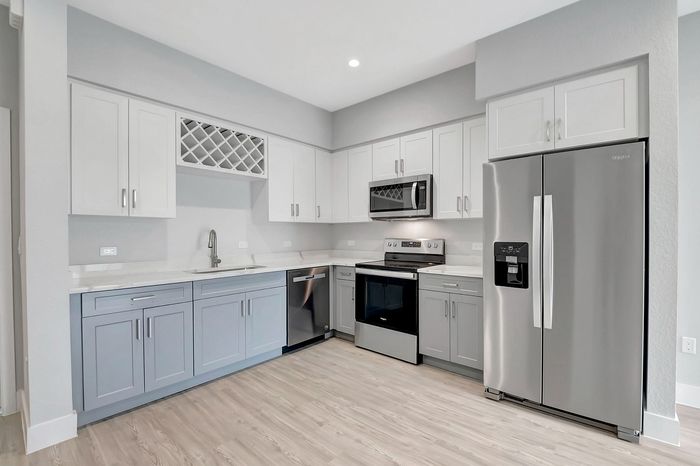 Modern kitchen with sleek stainless steel appliances, elegant white and gray cabinetry, and stylish light wood flooring, perfect for culinary creativity.