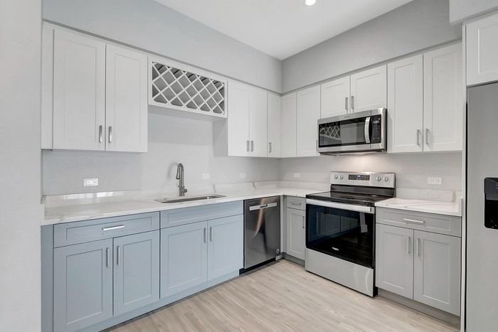 Modern kitchen with sleek white cabinetry, stainless steel appliances, and elegant light-toned flooring.