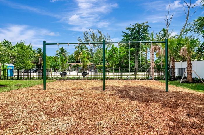 Inviting playground with swings nestled among lush greenery, perfect for family fun and relaxation.