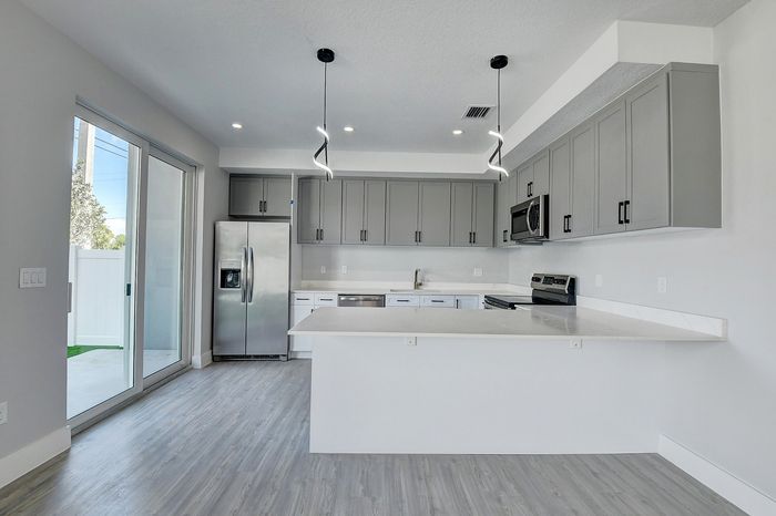 Modern kitchen with sleek gray cabinets, stainless steel appliances, and elegant pendant lighting highlighting a spacious quartz countertop island.