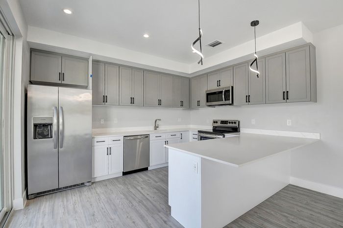 Modern kitchen with sleek gray cabinetry, stainless steel appliances, and elegant pendant lighting creating a stylish cooking space.