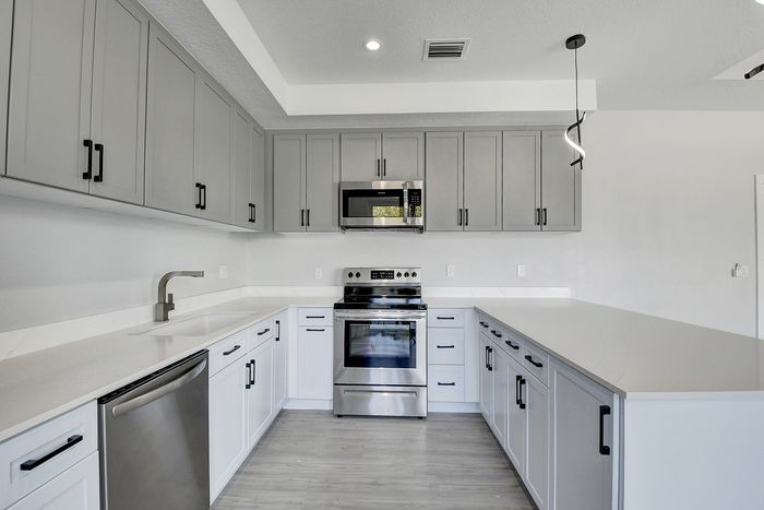 Modern kitchen with sleek gray cabinetry, stainless steel appliances, and elegant white countertops.