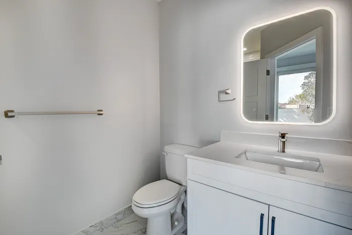 Chic modern bathroom featuring a sleek vanity with an LED mirror, stylish chrome fixtures, and elegant marble flooring.