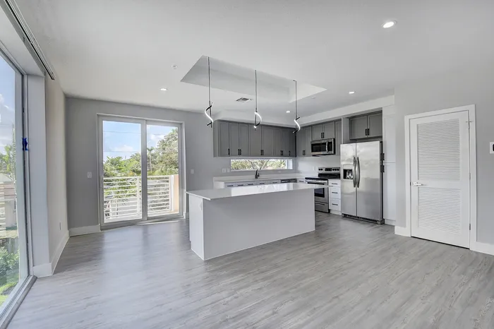 Sleek modern kitchen with stainless steel appliances, island, and large windows for natural light.
