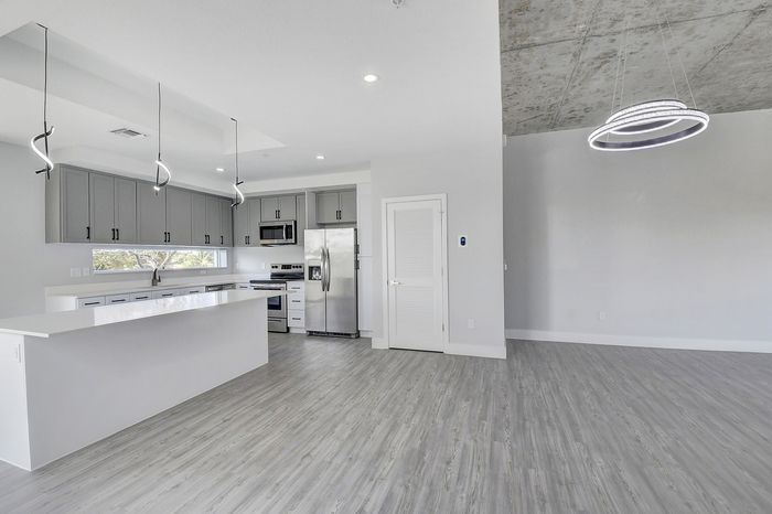 Modern open-concept kitchen with sleek grey cabinetry and stainless steel appliances, complemented by stylish pendant lighting and expansive living space.
