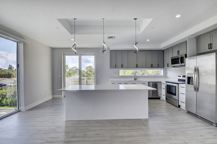 Modern open-concept kitchen with sleek stainless steel appliances, stylish pendant lighting, and large windows offering scenic views.