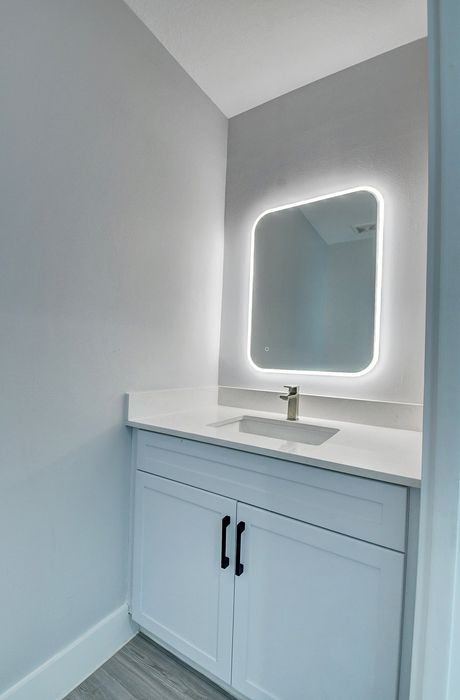 Elegant bathroom vanity with a sleek LED-lit mirror and contemporary faucet, perfect for modern living.