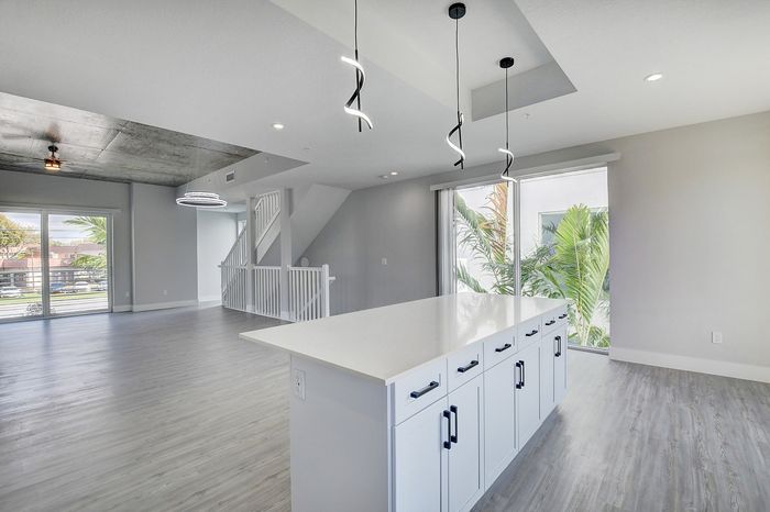 Modern open-concept living space featuring sleek overhead lighting, expansive windows, and a stylish kitchen island, perfect for entertaining.