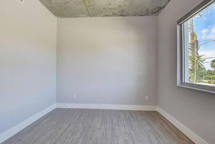 Bright and airy room with modern gray flooring and a large window offering a scenic view, ideal for a cozy living space.
