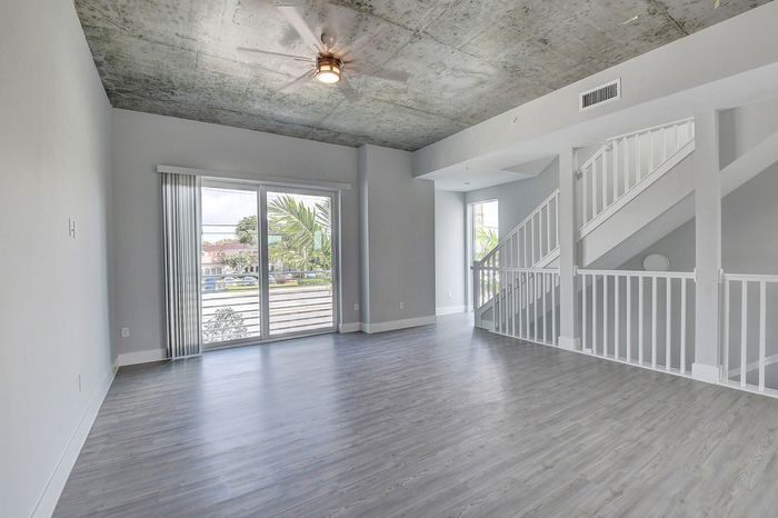Bright, modern living room with sleek laminate flooring, expansive window views, and stylish staircase leading to the upper level.