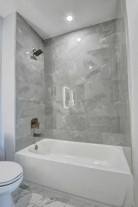 Elegant bathroom with luxurious marble tiles, a modern bathtub, and sleek fixtures creating a spa-like ambiance.
