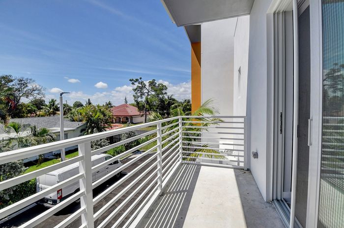 Inviting balcony with sleek railings and scenic views of lush greenery and charming neighborhood.