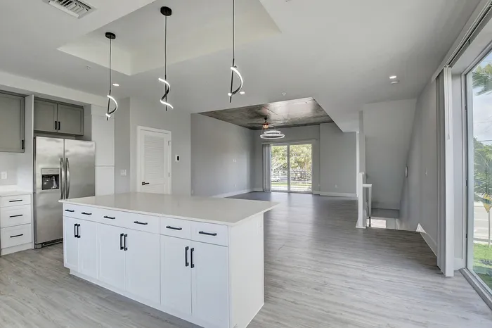 Contemporary open-concept apartment featuring a sleek kitchen with modern pendant lighting and a spacious, bright living area with large windows.