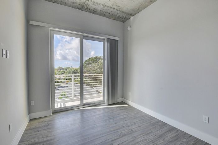Bright and airy room with modern flooring, large sliding glass doors, and a scenic balcony view.