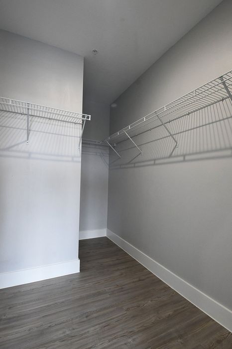 Spacious modern walk-in closet with sleek wire shelving and elegant wood flooring, perfect for organized storage.
