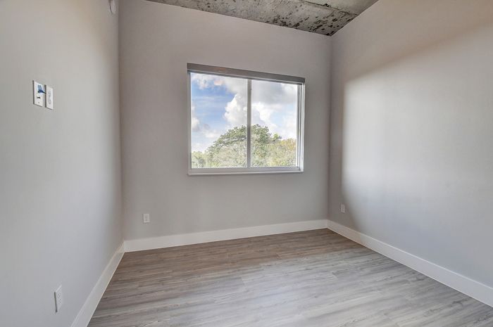Bright room with modern gray walls, large window, and stylish wood flooring.