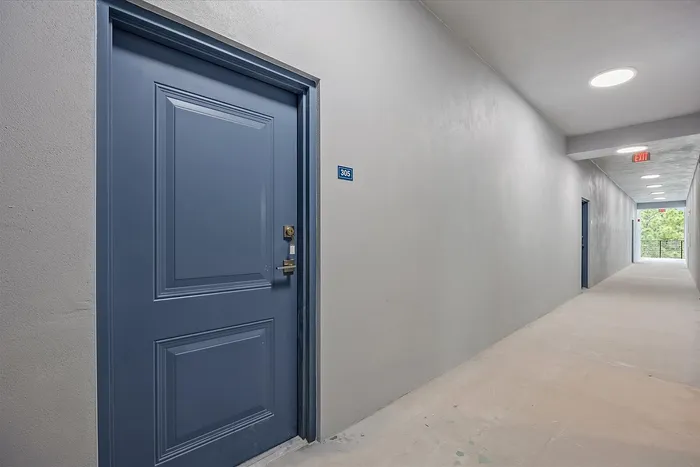 Contemporary apartment entrance with a sleek blue door and elegant hallway lighting.