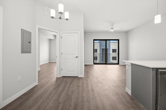 Modern apartment with sleek hardwood floors, open hallway, and large windows inviting ample natural light.