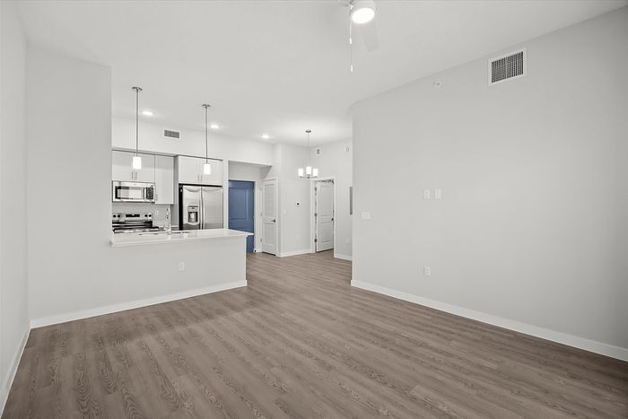 Bright, open-concept kitchen with modern stainless steel appliances and stylish lighting in a spacious apartment.
