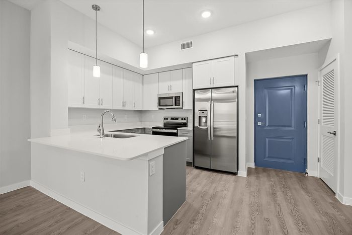 Modern kitchen with sleek stainless steel appliances, elegant white cabinetry, and inviting hardwood floors.