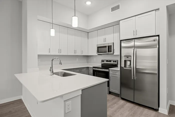 Modern kitchen featuring sleek stainless steel appliances, elegant white cabinetry, and a spacious quartz countertop island.