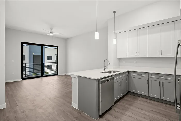 Modern, open-plan kitchen with sleek white cabinets and elegant lighting in a spacious apartment.