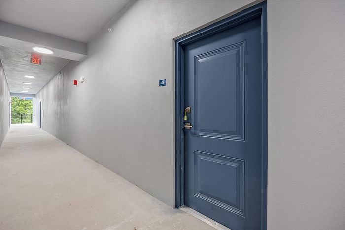 Sleek apartment hallway with modern lighting leading to unit 306, featuring a stylish blue door.