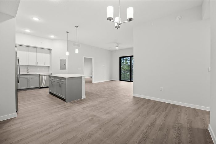 Modern open-concept apartment featuring a sleek kitchen with stainless steel appliances, expansive hardwood floors, and elegant lighting.