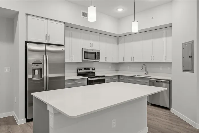 Sleek modern kitchen with stainless steel appliances, quartz countertops, and elegant pendant lighting.