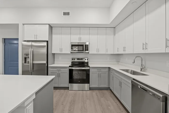 Modern kitchen featuring sleek stainless steel appliances, spacious white cabinetry, and elegant countertops.