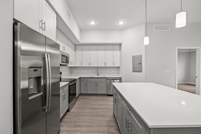 Modern kitchen with sleek stainless steel appliances, white cabinets, and a spacious island, ideal for culinary enthusiasts.