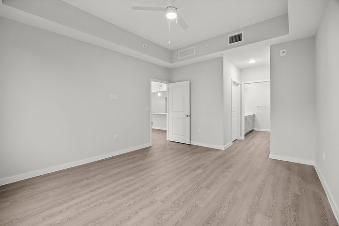 Bright and spacious empty room with modern wood flooring, elegant high ceilings, and neutral walls, perfect for personal customization.