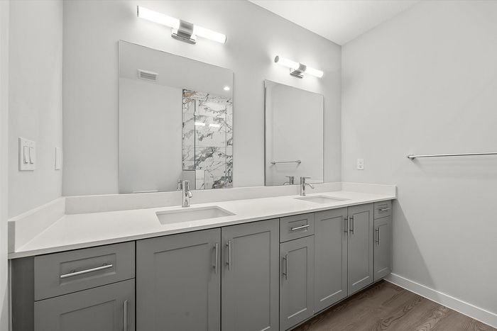 Elegant bathroom with double vanity sinks, modern lighting, and stylish marble accent shower.