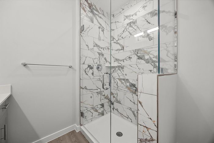 Elegant bathroom with luxurious marble-tiled shower and sleek glass door, offering a modern and stylish touch.