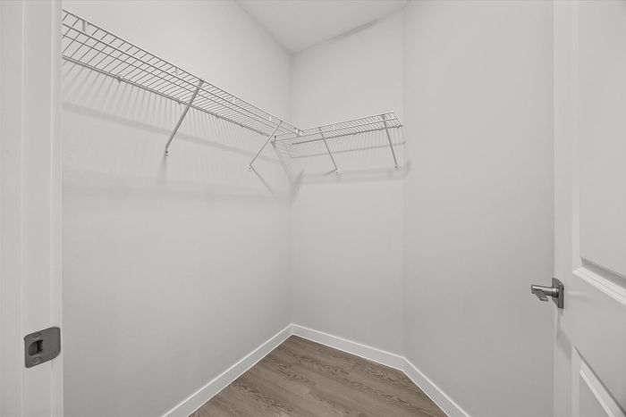 Spacious walk-in closet with sleek wire shelving and modern wood flooring, offering ample storage space and contemporary design.
