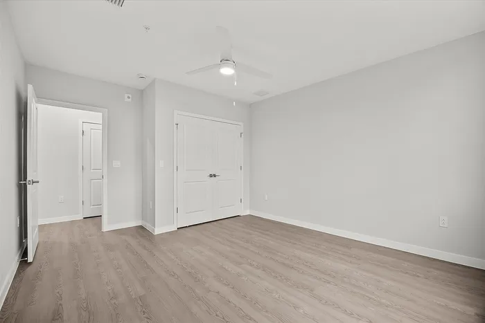 Bright and spacious bedroom with elegant hardwood flooring and dual closets, ready for personal touches.