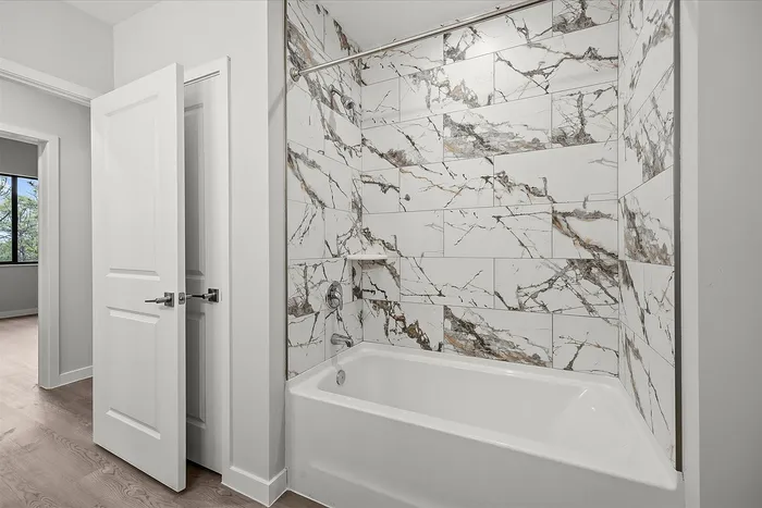 Elegant bathroom featuring luxurious marble tile walls and a modern bathtub, exuding a sense of sophistication and style.