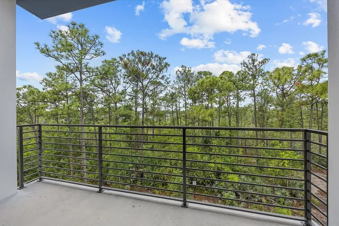 Charming balcony with serene forest view and bright blue sky, offering a peaceful retreat.