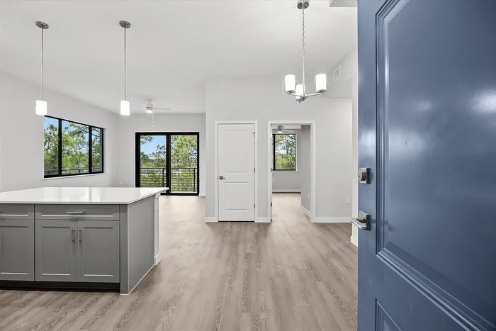 Bright and modern open-concept apartment with spacious kitchen island, large windows, and scenic balcony view.