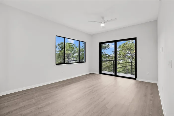 Bright and airy apartment room with elegant wood flooring, large windows, and a scenic balcony view.