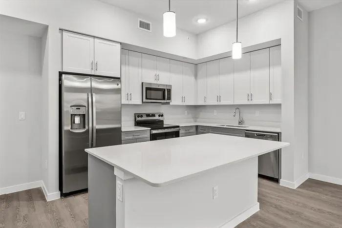 Modern kitchen with sleek stainless steel appliances, stylish white cabinets, and elegant pendant lighting over a spacious island.